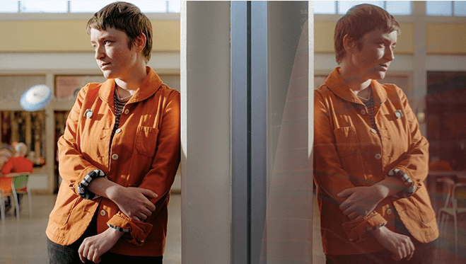 Boy Scouts sedang bersandar di dinding mengenakan jaket oranye